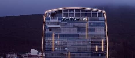 Un hotel moderno con fachada curva, varios pisos y ventanas iluminadas.