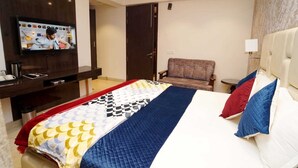 Una habitación de hotel con una cama, televisión, una silla y una mesita.