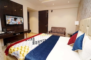 Una habitación de hotel con una cama, televisión, una silla y una mesita.