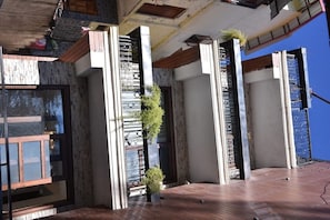 Un edificio moderno con fachada de piedra, ventanas amplias y un balcón con suelo de madera.