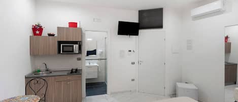 Una habitación moderna y luminosa con kitchenette, comedor y cama.