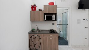 A compact kitchen with a microwave, sink, and a small countertop. - Standard Studio Apartment with Wi-Fi and Air Conditioning (Salerno)