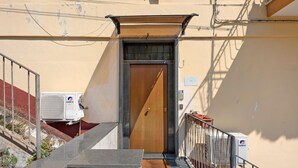 A narrow stairway leading to a wooden door with a metal gate, a GREE air conditioning unit, and a small outdoor area with a metal railing. - Standard Studio Apartment with Wi-Fi and Air Conditioning (Salerno)