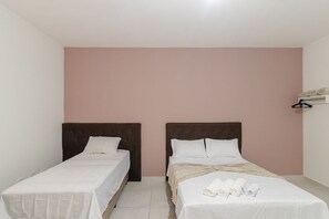 Une chambre avec deux lits simples, un mur rose et un plafond blanc.