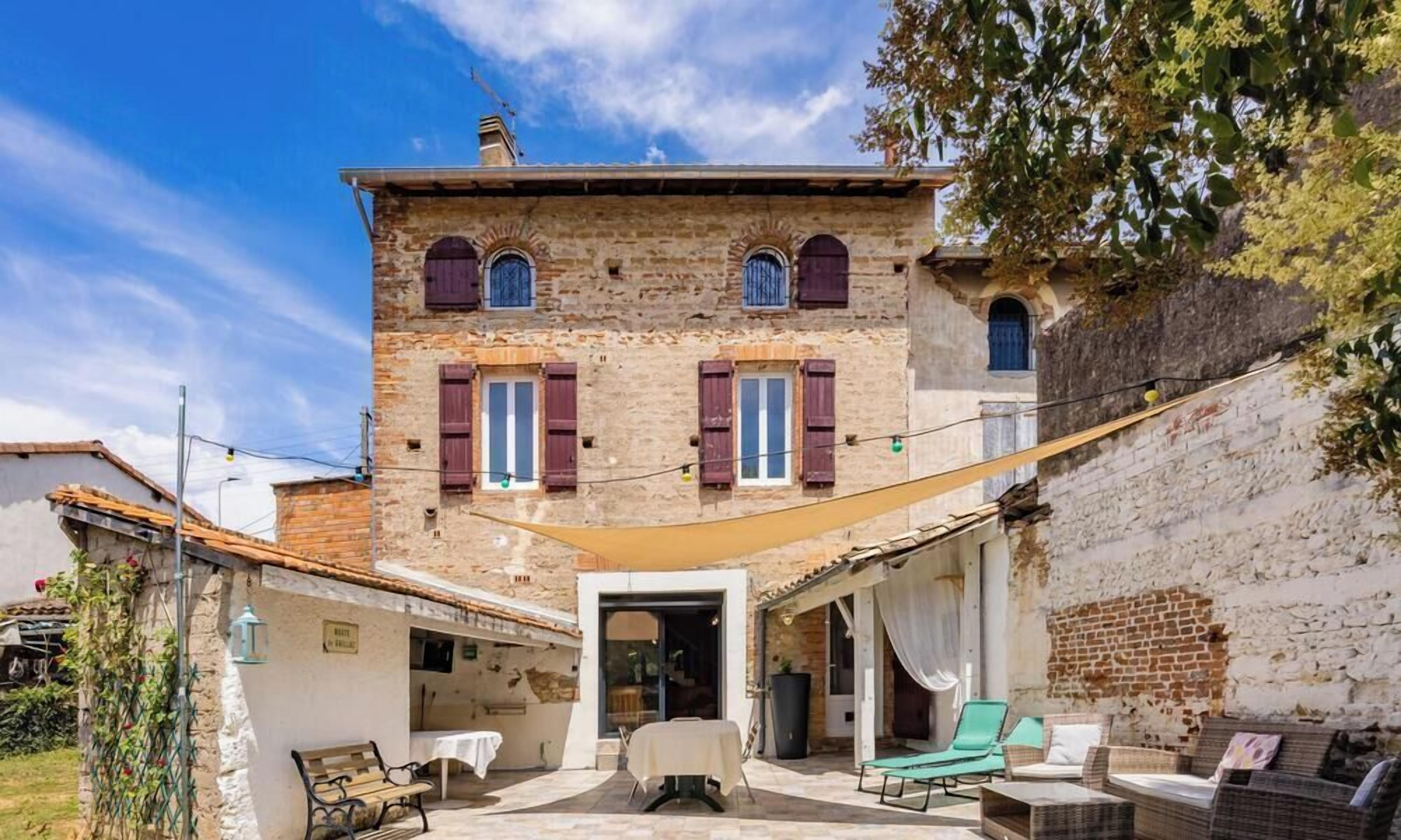 A two-story building with a courtyard, featuring a dining area with outdoor furniture and a covered seating area.