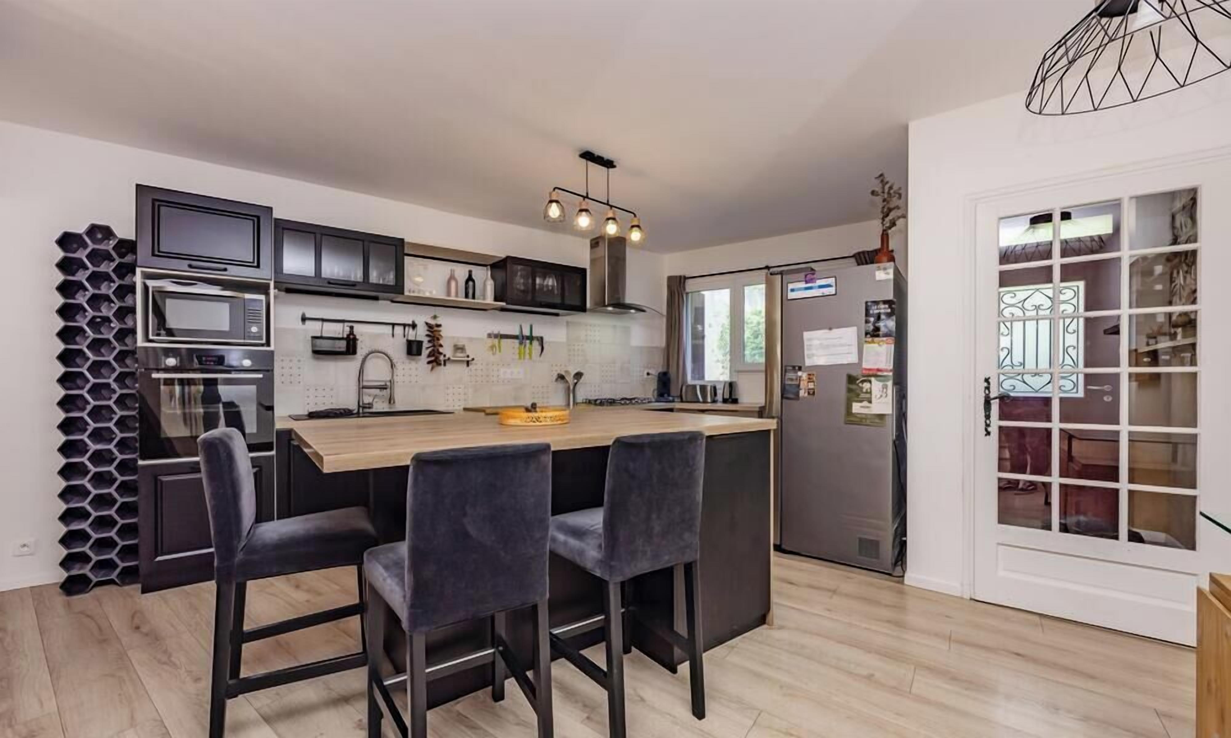 A modern kitchen with a central island, built-in appliances, and a dining area with bar stools.