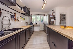 Eine moderne Küche mit einer zentralen Kochinsel, Edelstahlgeräten und einem Fenster, das für natürliches Licht sorgt.
