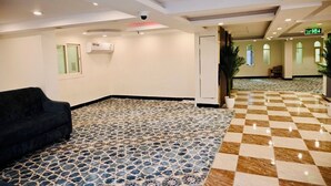 A hotel lobby with a patterned floor, a black sofa, and a ceiling with recessed lighting and a security camera. - Sari Almisk Hotel (Makkah)