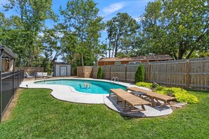 A backyard with a swimming pool, wooden deck, and lounge chairs. - Swimming Pool, Hot Tub, Bike-In/Out, Fire Pit, Ping Pong and Snow Cone Machine (Bentonville)