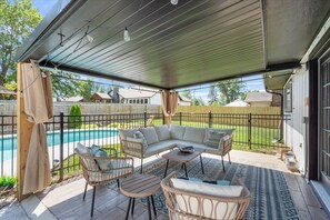 A covered patio with outdoor furniture, a pool, and a view of the backyard.