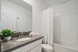 A bathroom with a sink, mirror, toilet, and shower curtain. - ChampionsGate Villa: Pool, Golf Theater & F1 (Davenport)