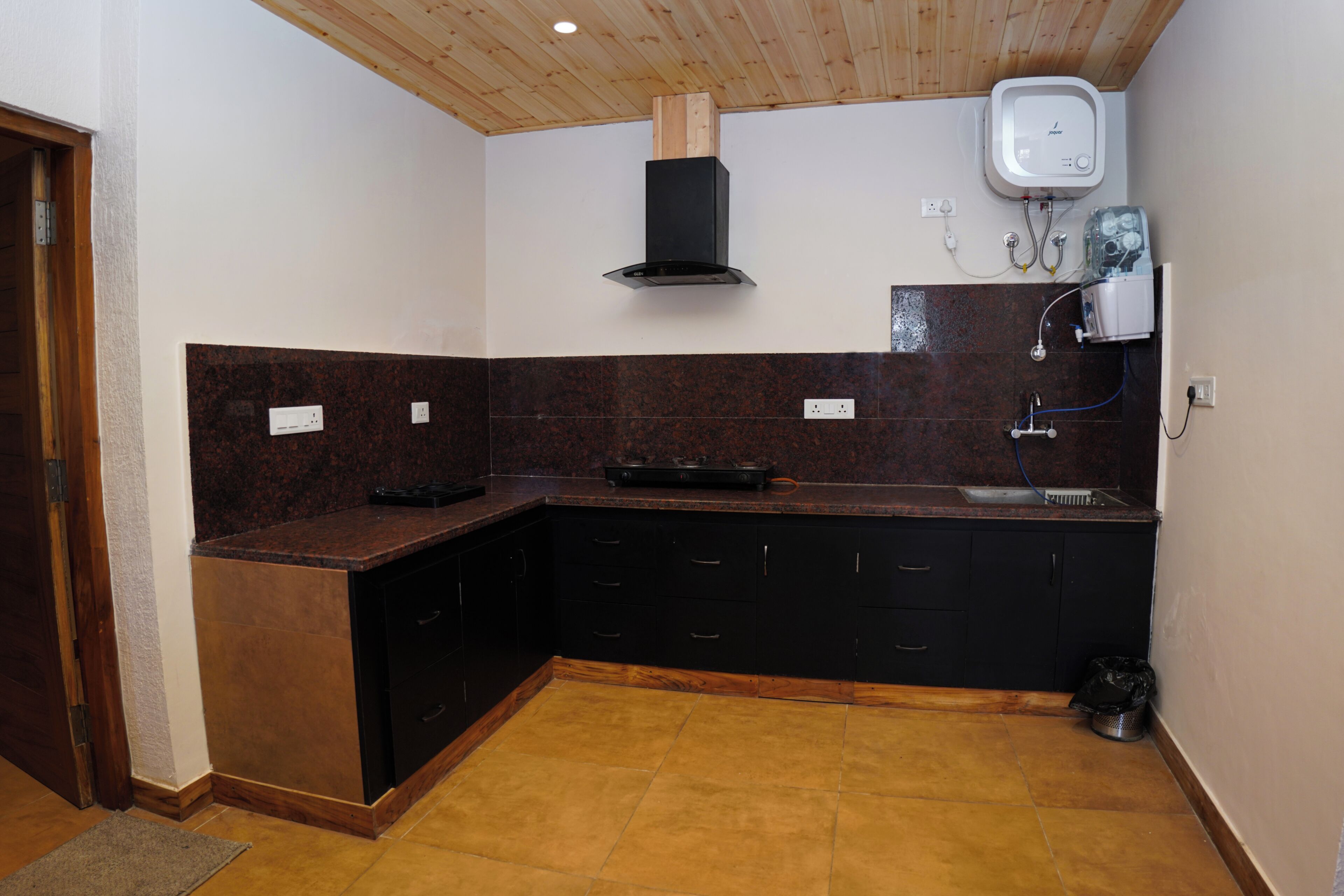 A compact kitchen with dark cabinetry, a built-in oven, and a modern range hood.