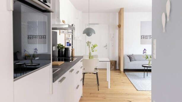 Eine moderne Küche mit Essbereich, einer Couch und einer Pendelleuchte.