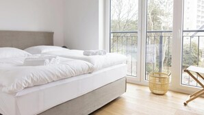 Ein Schlafzimmer mit Bett, Fenster und Balkon.