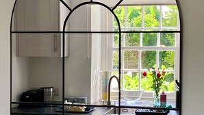 A kitchen with a large window, cabinets, a sink, and a chair. - Laundry Cottage: a little piece of heaven in North Cornwall! (Bodmin)