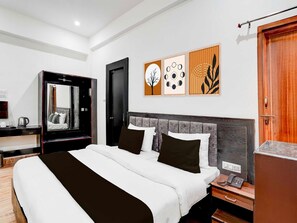 A modern hotel room with a large bed, a bedside table with a phone, a mirror, and artwork on the wall. - Townhouse Sarnath Temple (Varanasi)