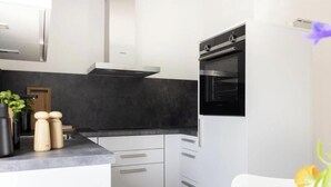 Eine moderne Küche mit weißen Schränken, einer schwarzen Arbeitsplatte und einem eingebauten Backofen.