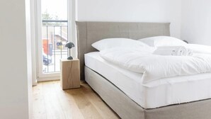 Ein Schlafzimmer mit einem Bett, einem Nachttisch, einem Fenster und Blick nach draußen.