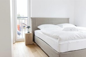 Une chambre à coucher avec un lit, une table de chevet, une fenêtre et une vue sur l’extérieur.