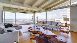 A spacious living room with a high ceiling, large windows offering a city view, a leather coffee table, and a sofa. - 4 Mi to Beach! Ocean-view Group Haven in Honolulu (Honolulu)