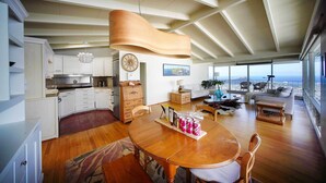 A spacious living area with a wooden dining table, a sofa, and a large window offering a view of the city. - 4 Mi to Beach! Ocean-view Group Haven in Honolulu (Honolulu)