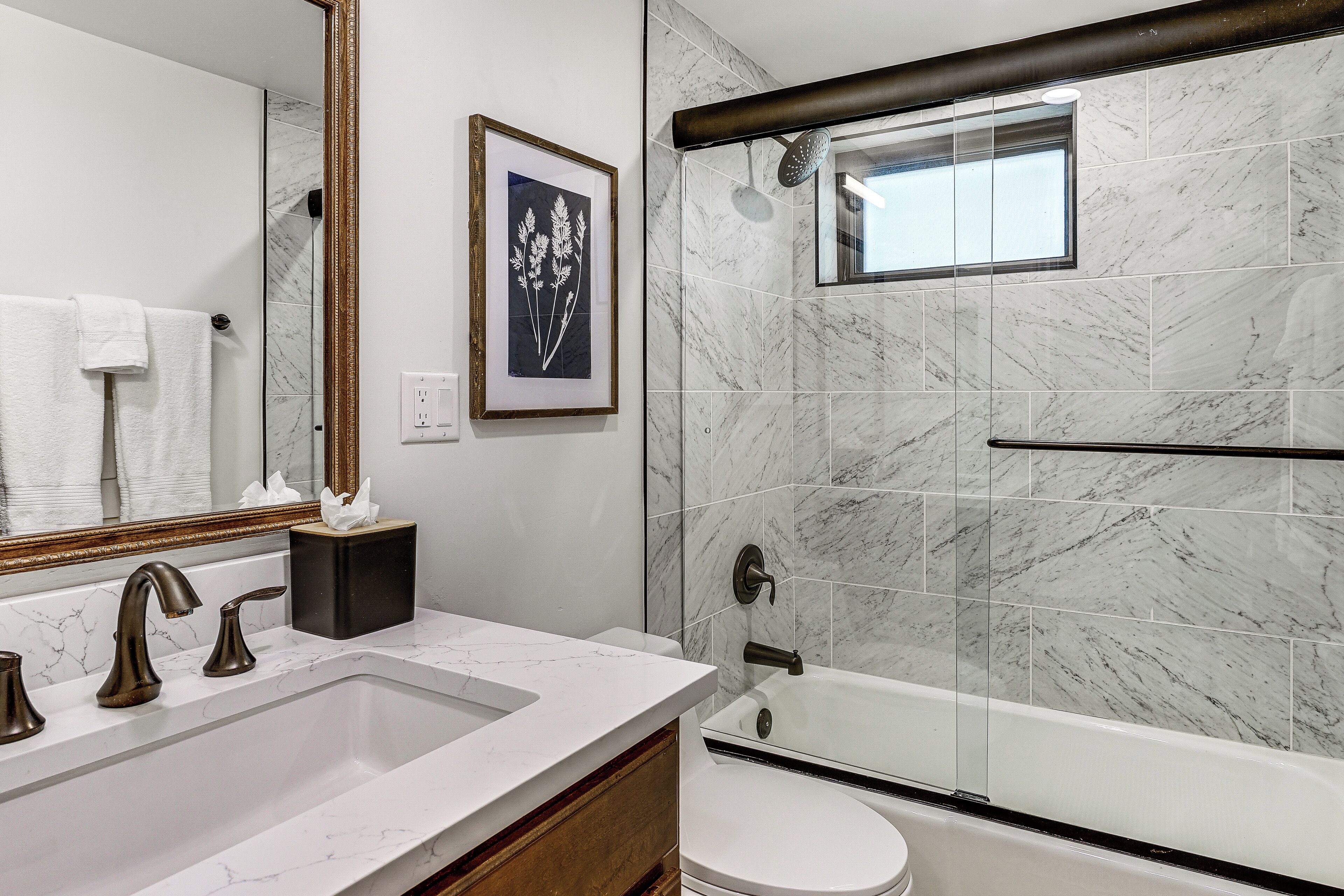 A bathroom with a marble sink, a bathtub, and a shower.