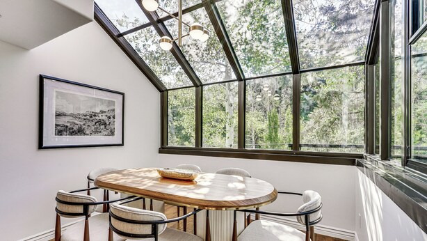A dining area with a round table, six chairs, a framed picture on the wall, and large windows with a view of trees. - Park City Gem w/ Hot Tub + Sauna: Walk to Main St (Park City)