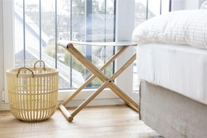 Ein Zimmer mit einem Bett, einem Fenster mit Blick, einem Holzboden und einem gewebten Korb.