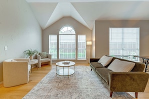 A living room with a high ceiling, a round coffee table, a sofa, and a chair. - 4 Mi to Toyota Stadium! Family Haven w/ Pool Oasis (Frisco)