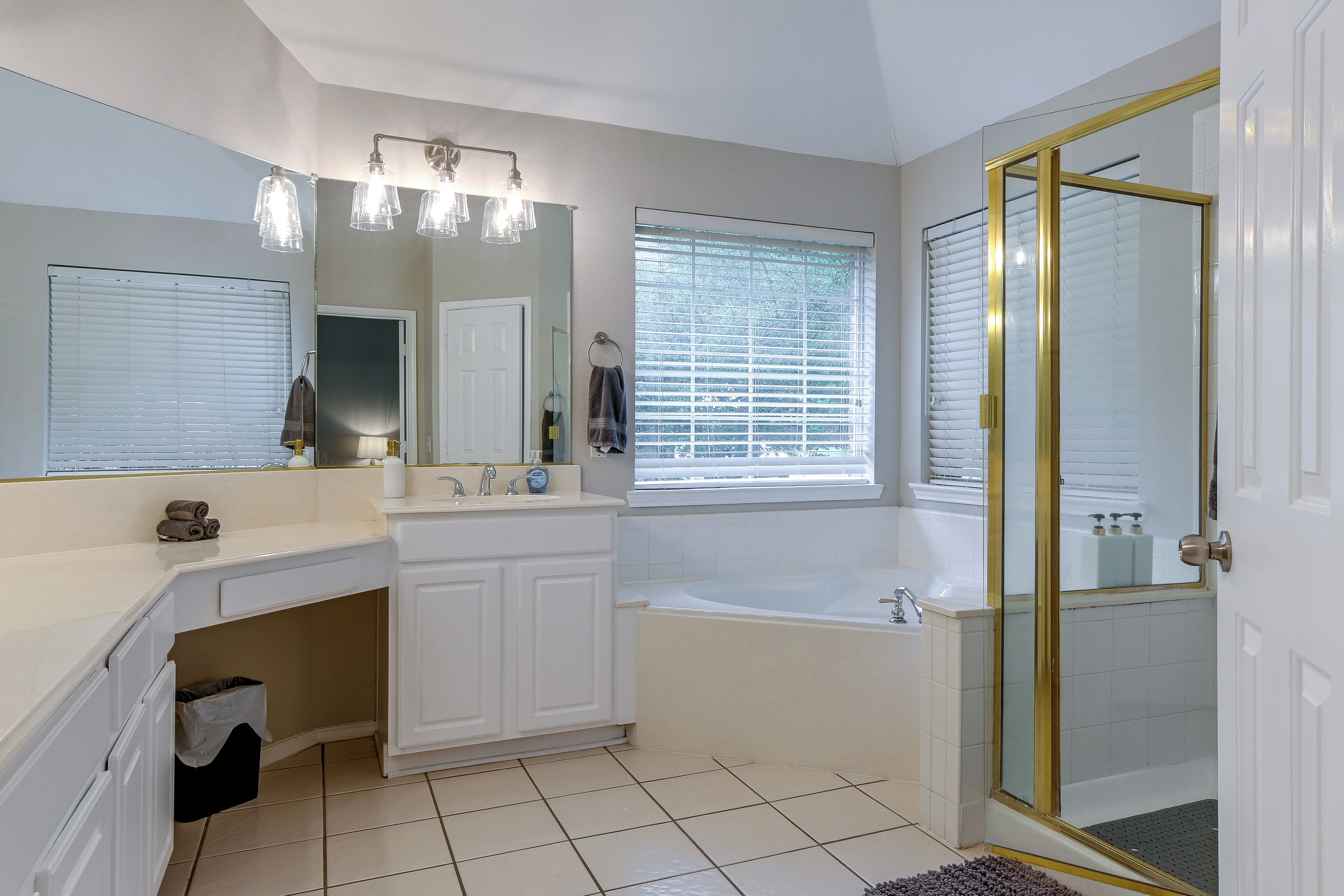 A modern bathroom with a vanity, mirror, bathtub, and shower.