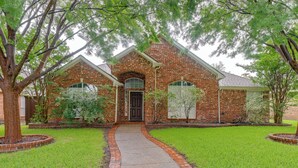A brick house with a front entrance, a pathway leading to the door, and a well-maintained lawn. - 4 Mi to Toyota Stadium! Family Haven w/ Pool Oasis (Frisco)