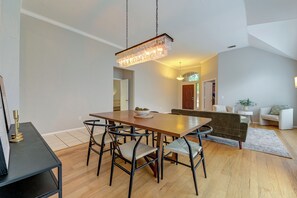 Ein Essbereich mit Holztisch, schwarzen Metallstühlen und einer hängenden Leuchte.