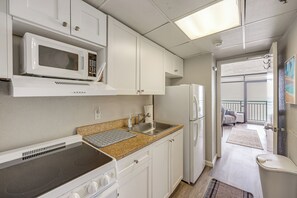 Una cocina compacta equipada con microondas, estufa, lavabo y refrigerador.