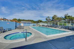 Ein Poolbereich mit Liegestühlen, einem Whirlpool und einer umzäunten Terrasse.