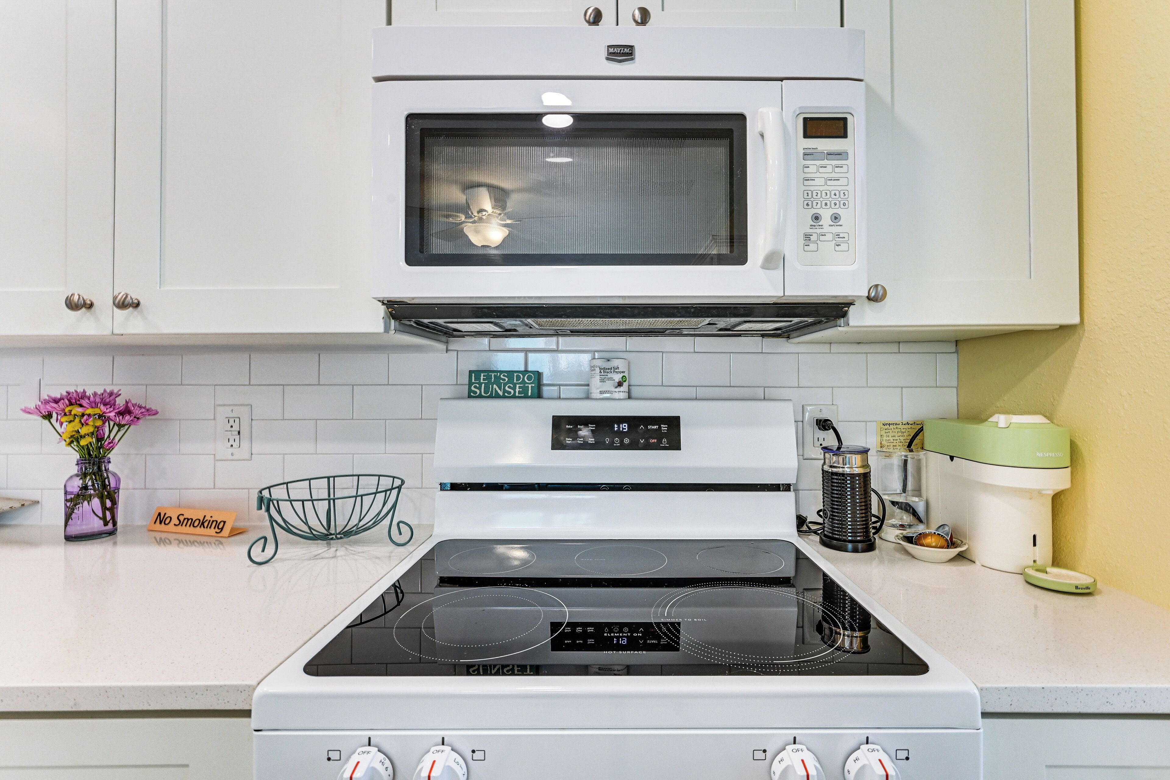 Une cuisine équipée d’un four à micro-ondes, d’une cuisinière et d’un panneau indiquant qu’il est interdit de fumer.