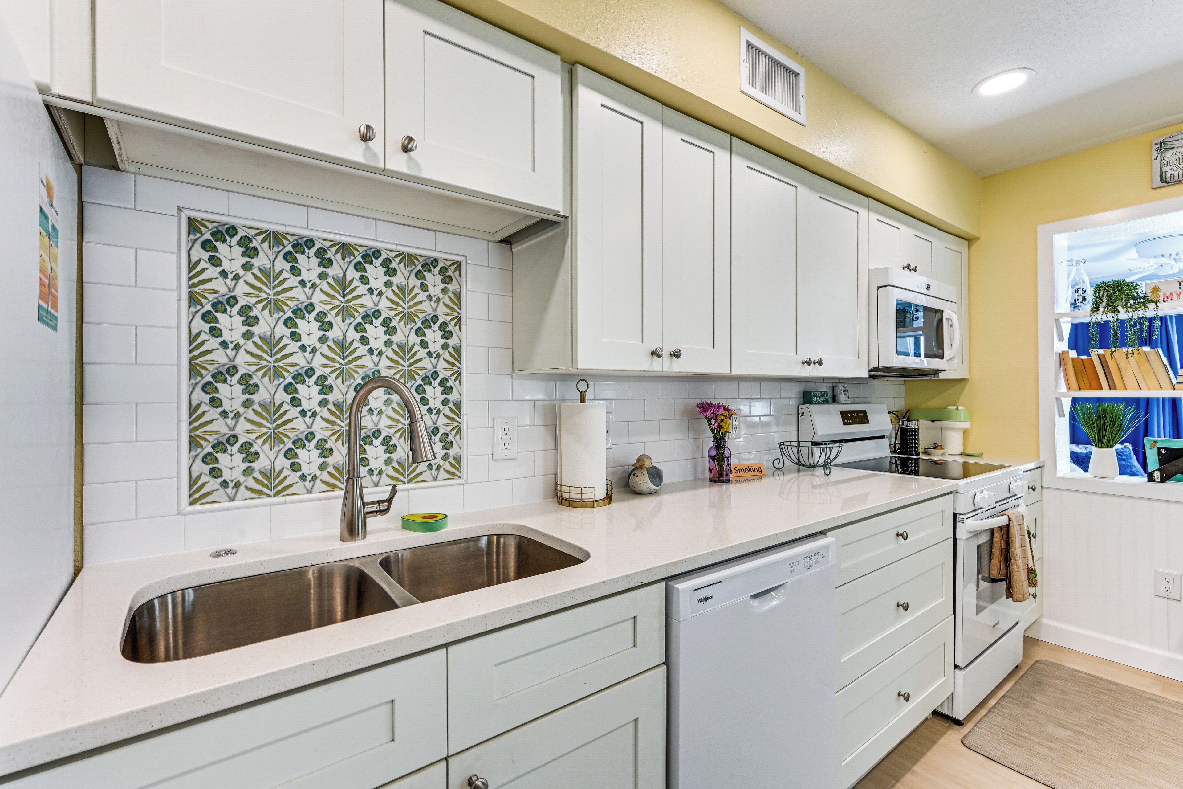 A kitchen with white cabinets, a stainless steel sink, a microwave, and a dishwasher.