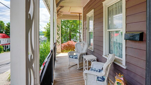 A porch with wicker furniture and a view of the street.