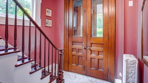 A staircase leading to a wooden door with glass panels, a white radiator, and framed artwork on the wall.