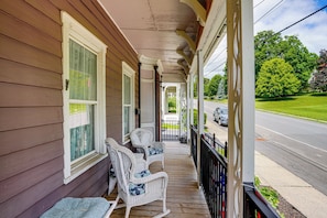 A porch with two rocking chairs, a covered walkway, and a view of a street with cars and greenery. - Peaceful Upstate Retreat! Walk to Hudson River (Coxsackie)