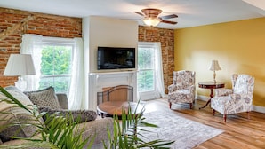 A living room with a fireplace, television, and patterned armchairs.