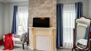 A room with a fireplace, a television, a bed, and a mirror.