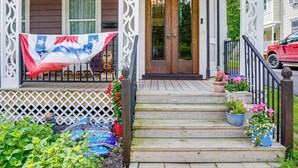 A wooden porch with steps, a flag, and potted plants.