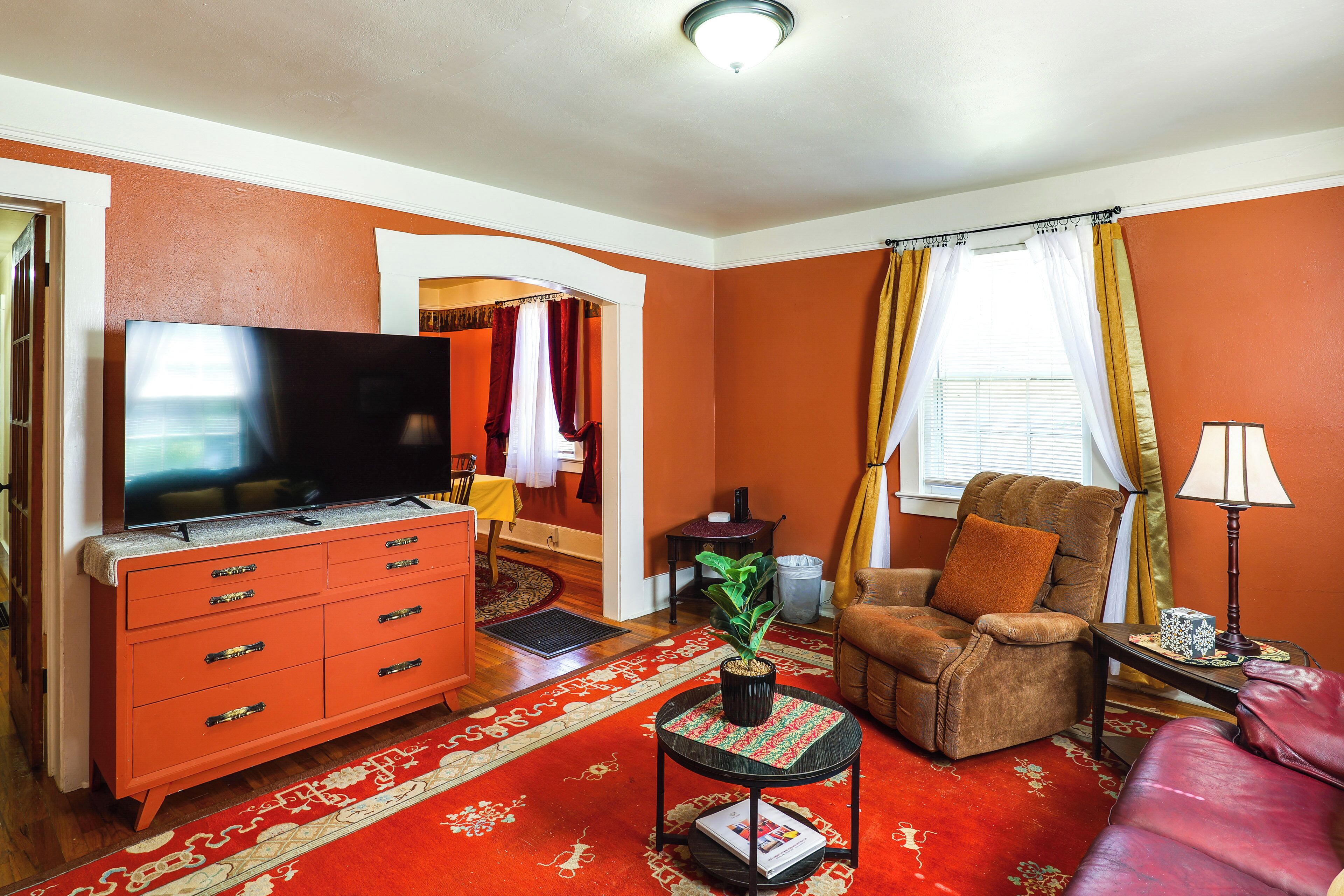 A living room with a television, a sofa, a chair, a small table, and a potted plant.