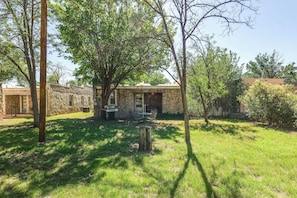 A stone building with a patio, surrounded by trees and grass.
