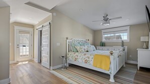A bedroom with a bed, a ceiling fan, a window, and a door. - Downtown Lewes on 2nd Street - #104 - 2nd floor apartment (Lewes)