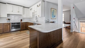 A modern kitchen with white cabinetry, a marble countertop, and a wooden floor. - Downtown Lewes on 2nd Street - #104 - 2nd floor apartment (Lewes)
