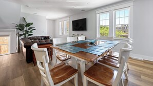 A dining area with a wooden table, white chairs, and a brown leather sofa. - Downtown Lewes on 2nd Street - #104 - 2nd floor apartment (Lewes)