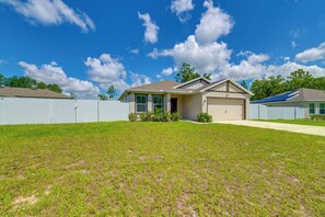 A residential house with a garage, a fenced yard, and a clear blue sky.