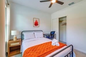 A neatly arranged bedroom with a bed, a bedside table with a lamp, a chair, and a closet.