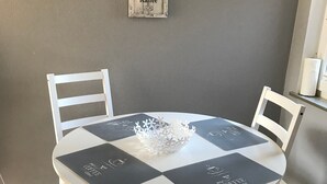 Ett runt bord med en vit och svart rutig duk, omgivet av fyra vita stolar med svarta kuddar.